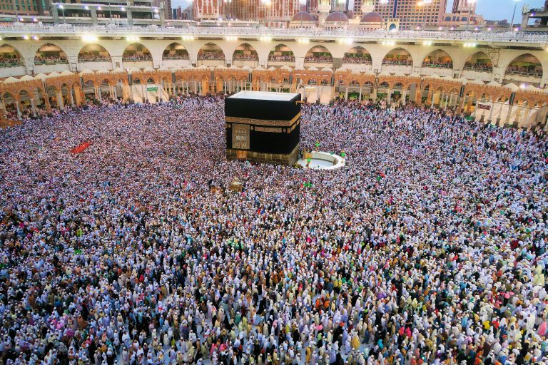 Aerial view of a large crowd of pilgrims gathered around the Kaaba in Mecca for religious rituals.